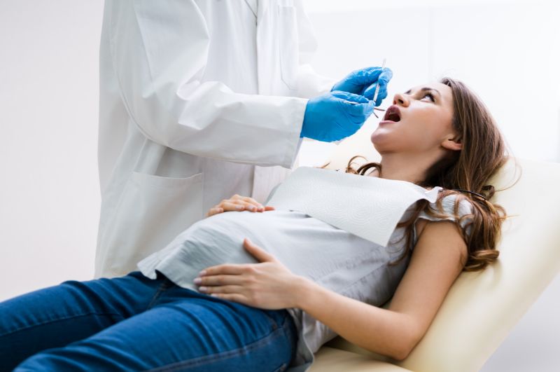 uśmiechnięta kobieta w ciąży czeka na stomatologa